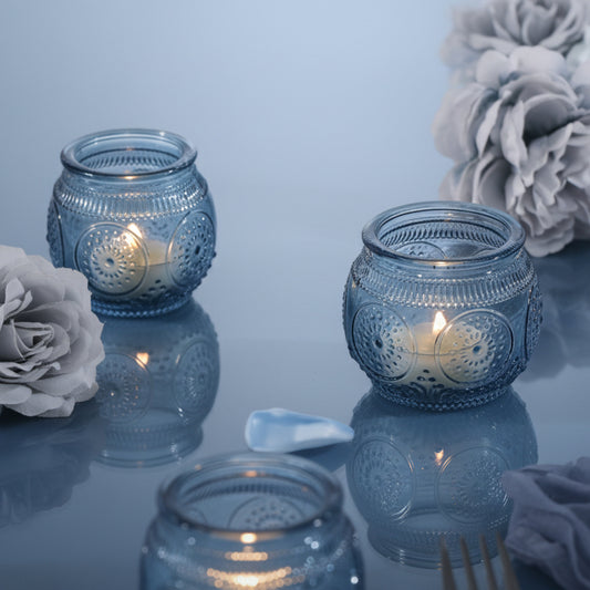 Blue glass votive candle holder glowing softly with a lit tea light in a calm setting
