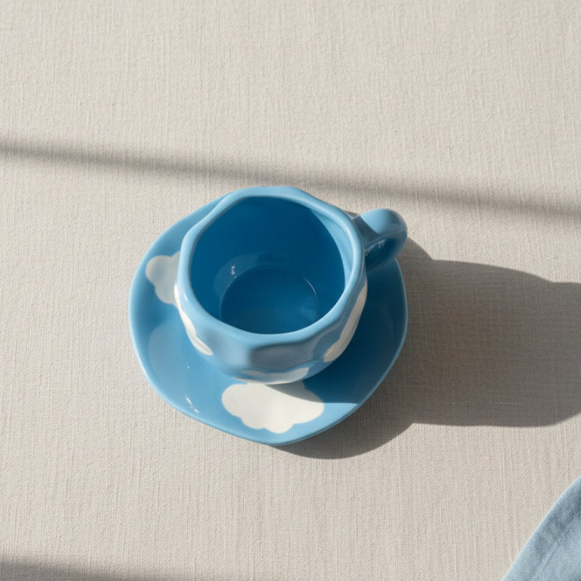 Close-up of cool blue ceramic mug with white cloud pattern and matching saucer
