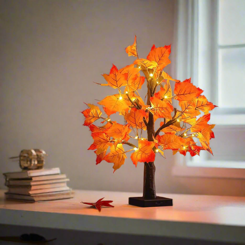 Cozy autumn maple leaf LED tree lamp glowing on wooden chair for fall home decor