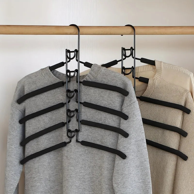 Black multi-clip hanger holding two sweaters on a wooden rod.